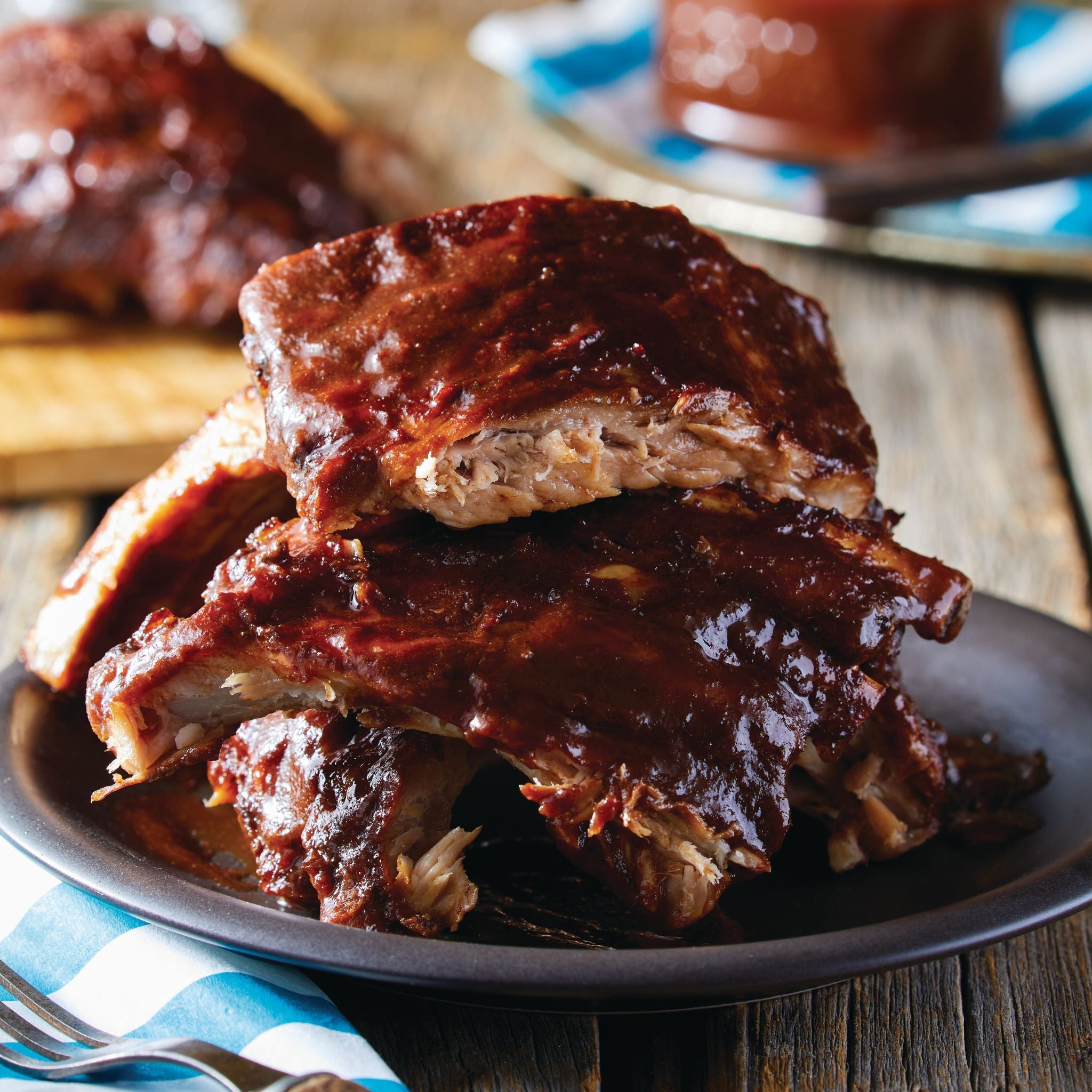 Stack of ribs with barbecue sauce on a plate on a wooden table
