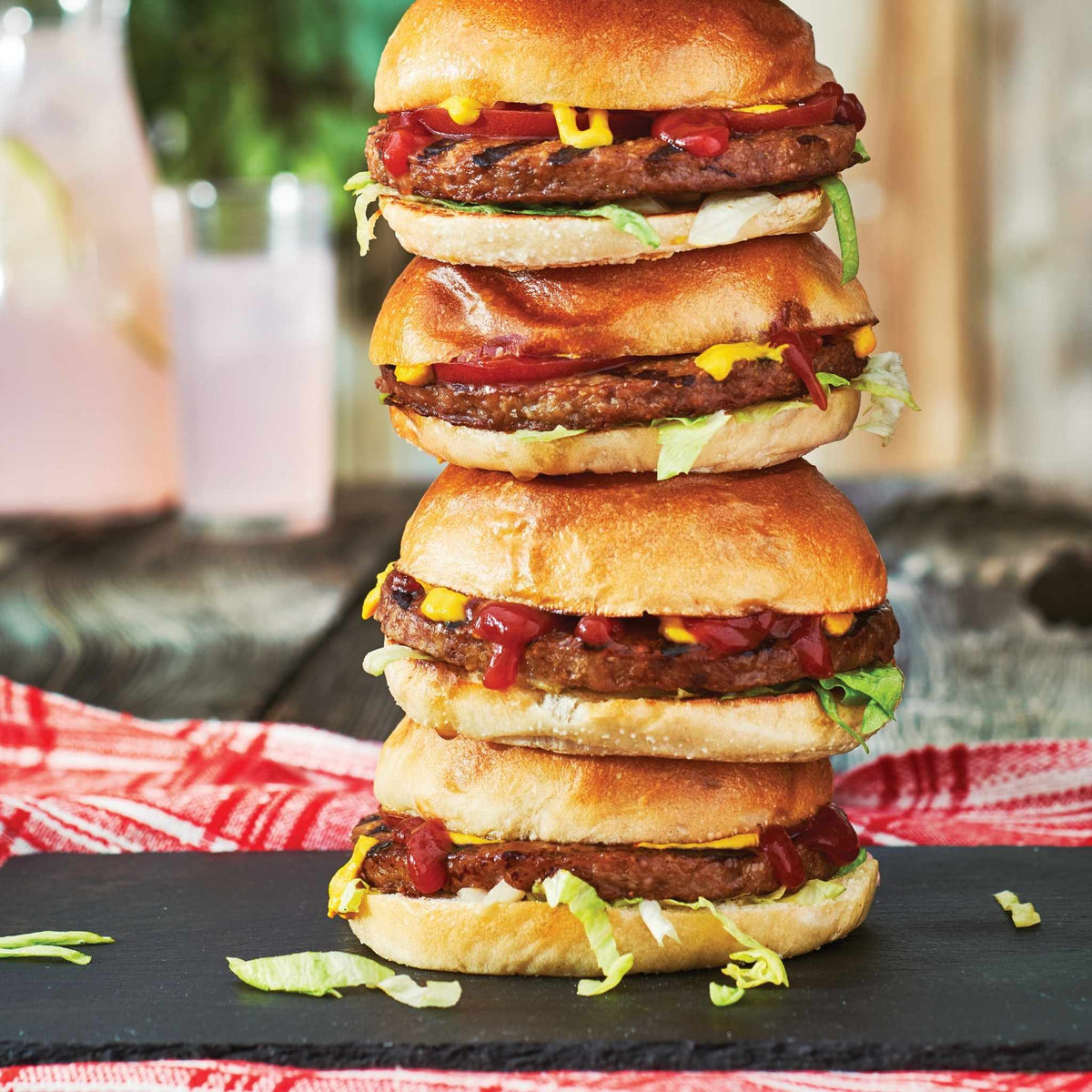 Stack of four Tasty Burgers on a black slate surface