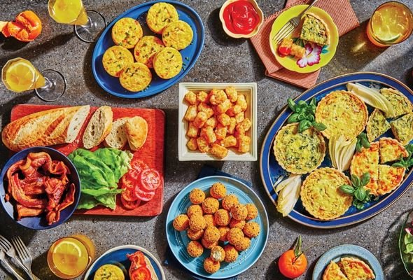 Assorted breakfast food items including bread, vegetables, and tater tots on a table.