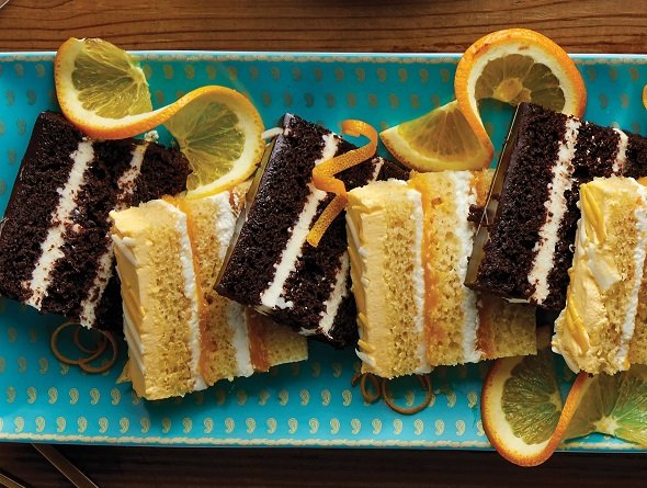 Slices of cake with lemon and orange garnishes on a blue tray.