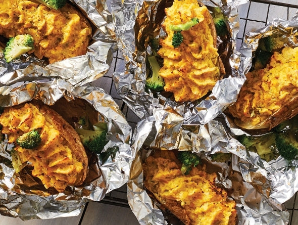 Grilled Stuffed Potatoes in tinfoil on a cooling rack.