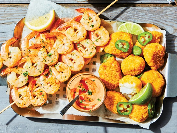Platter of cooked from frozen seafood and a dipping sauce on a wooden surface