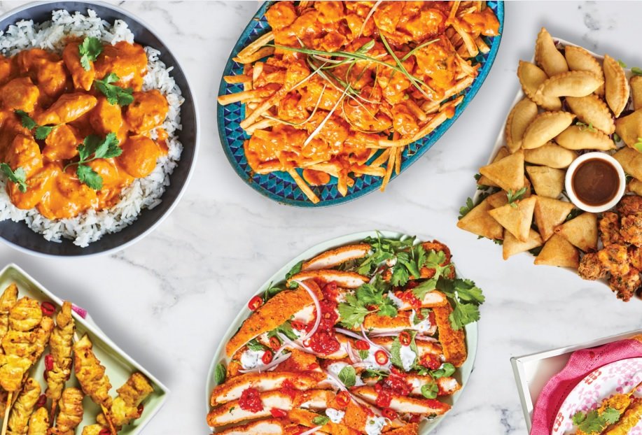 Assorted frozen prepared dishes including chicken, fries, and bread on a white marble surface