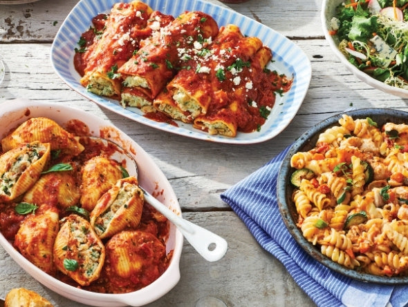 Three plates of pasta dishes on a wooden table