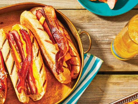 Turkey sausages on buns topped with bacon and cheese