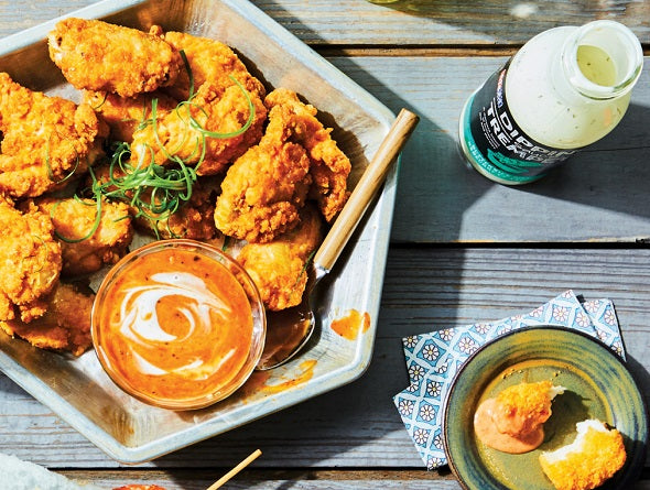 Breaded Chicken Wings with a side of dipping sauce on a wooden table